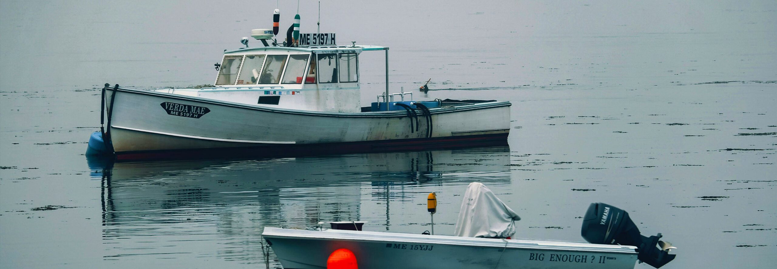 A Maine Lobster boat sits idly in calm New England waters.
