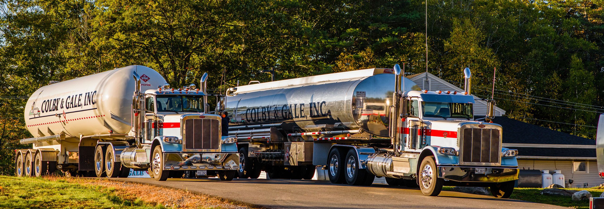 Two large fuel trucks line up next to each other by the Colby & Gale blue office building.
