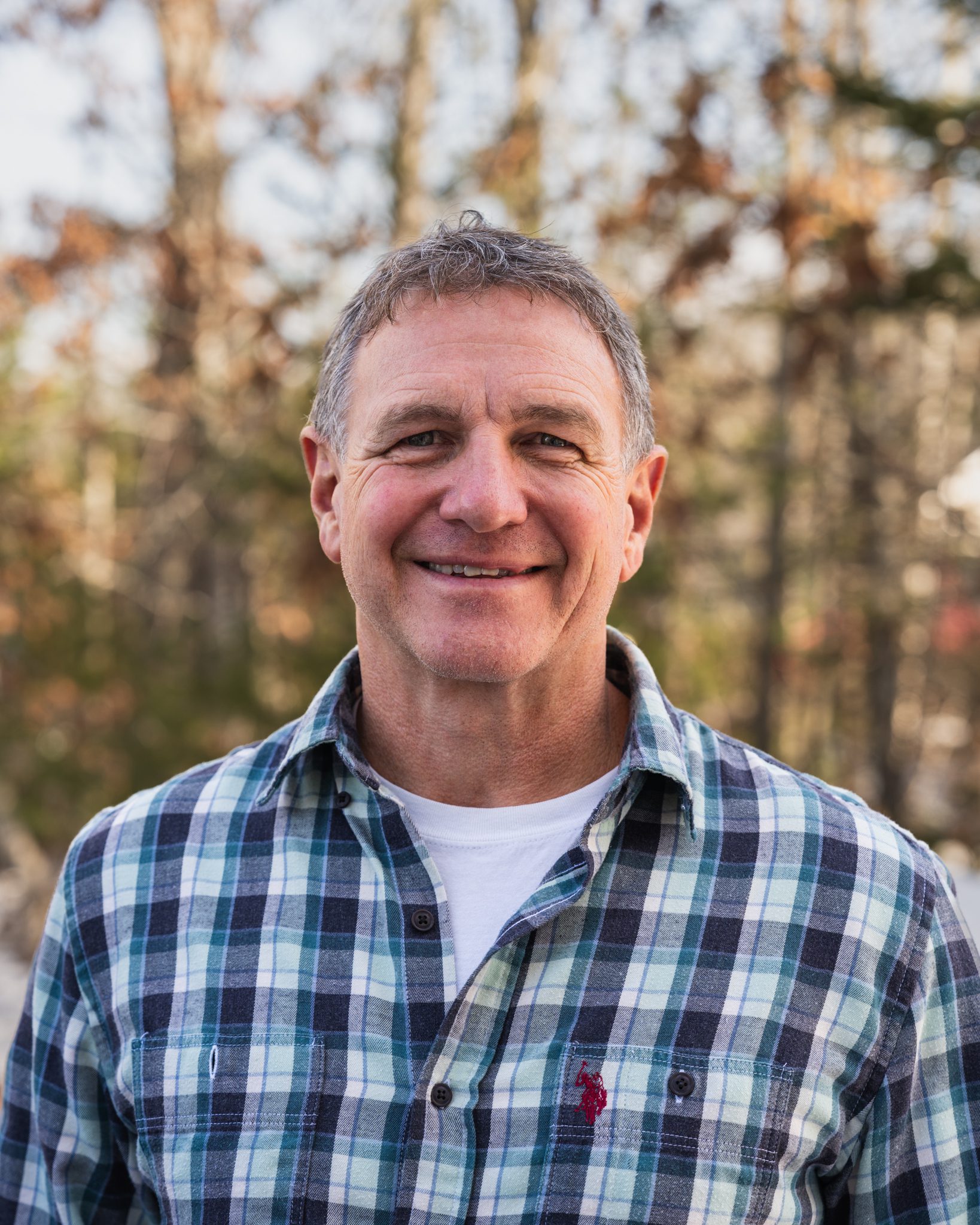 Cappy Dean, Operations Manager wearing a checkered Polo Ralph Lauren shirt smiles at the camera.