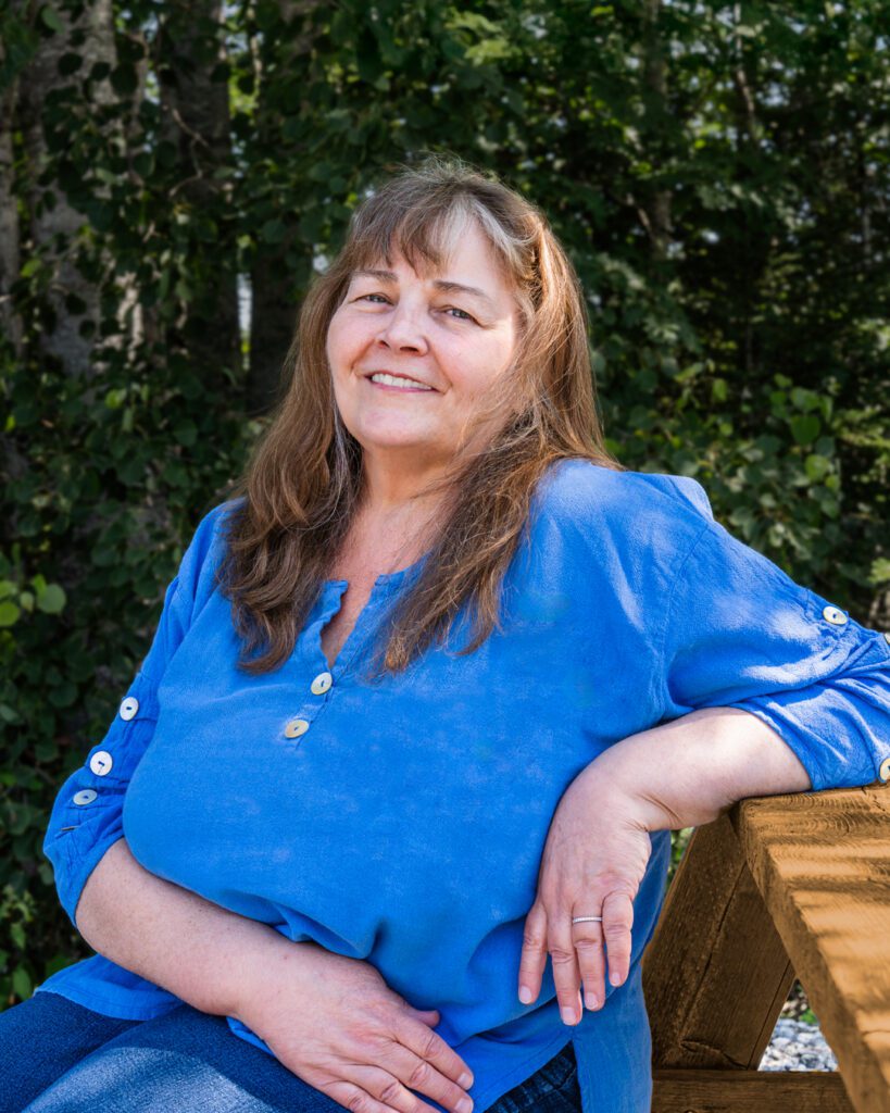 Cindy Williams sitting on picnic bench with one arm on table.