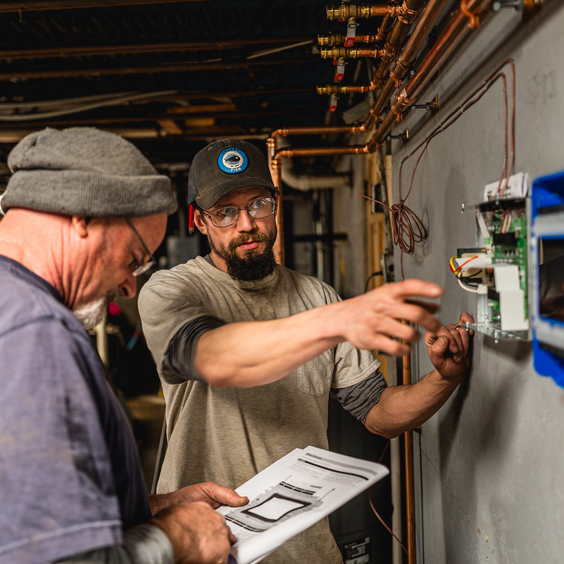 A man wears protective eyewear while working in a basement on an expansion tank.