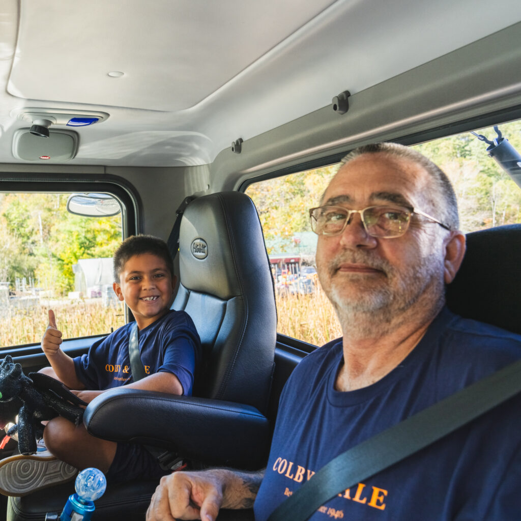 Dennis and grandson smiling inside transport truck at Pumpkinfest Parade.