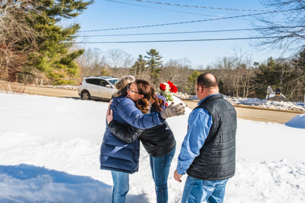 Kelsey Cole hugging a customer   while Rob Wilkes looks on.