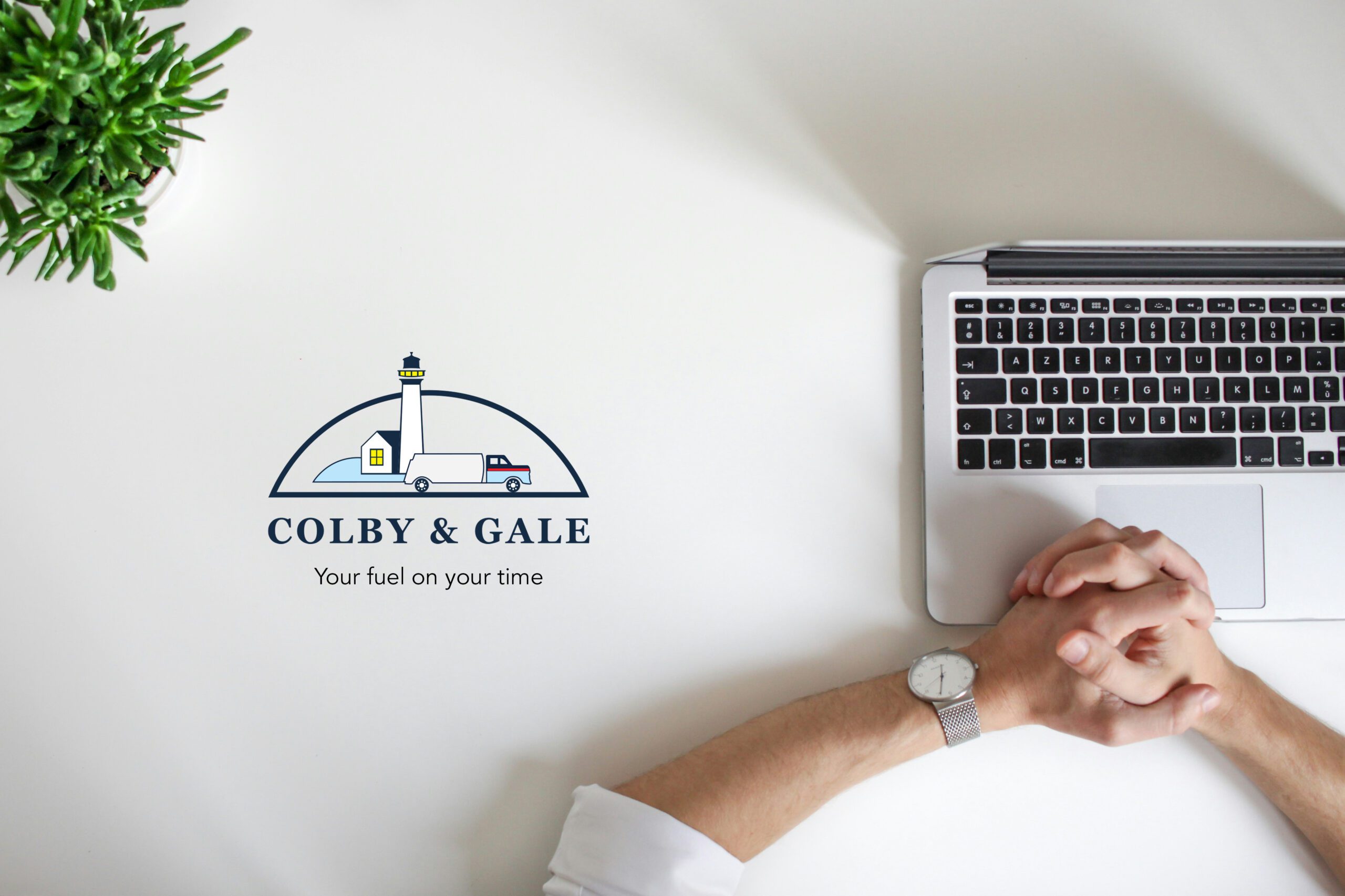 hands crossed on top of laptop on table with Colby & Gale logo off to the side.