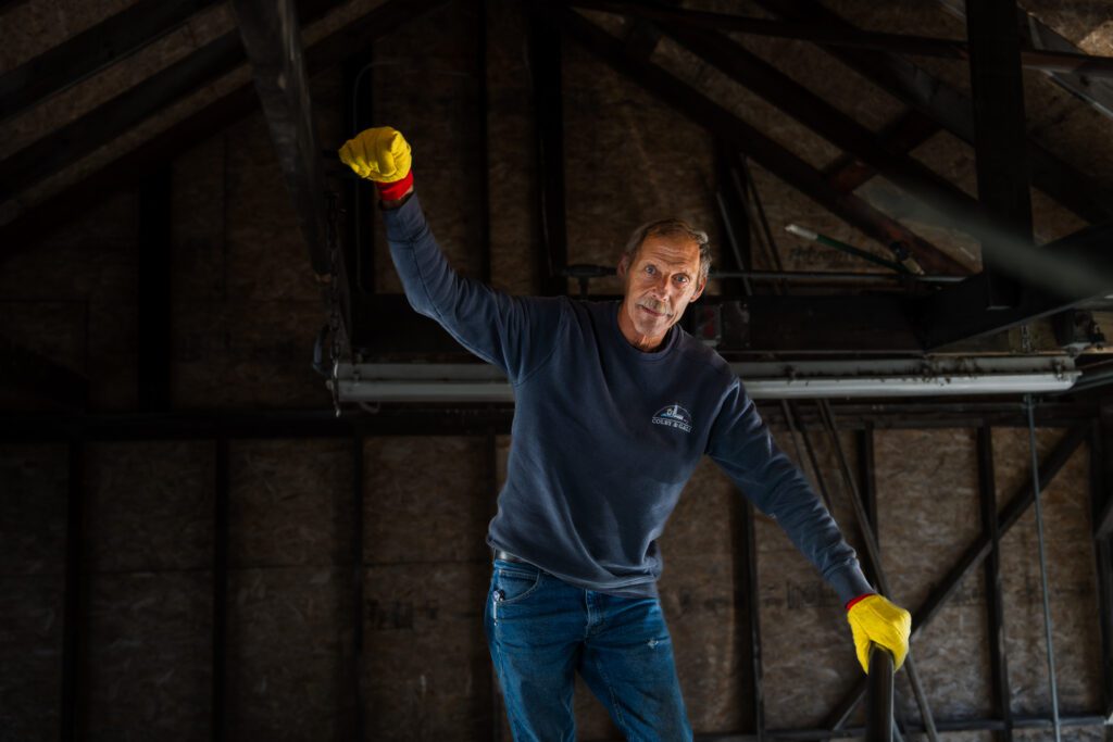 John Murphy wearing yellow glove with arms outstretched standing on top of an oil truck.