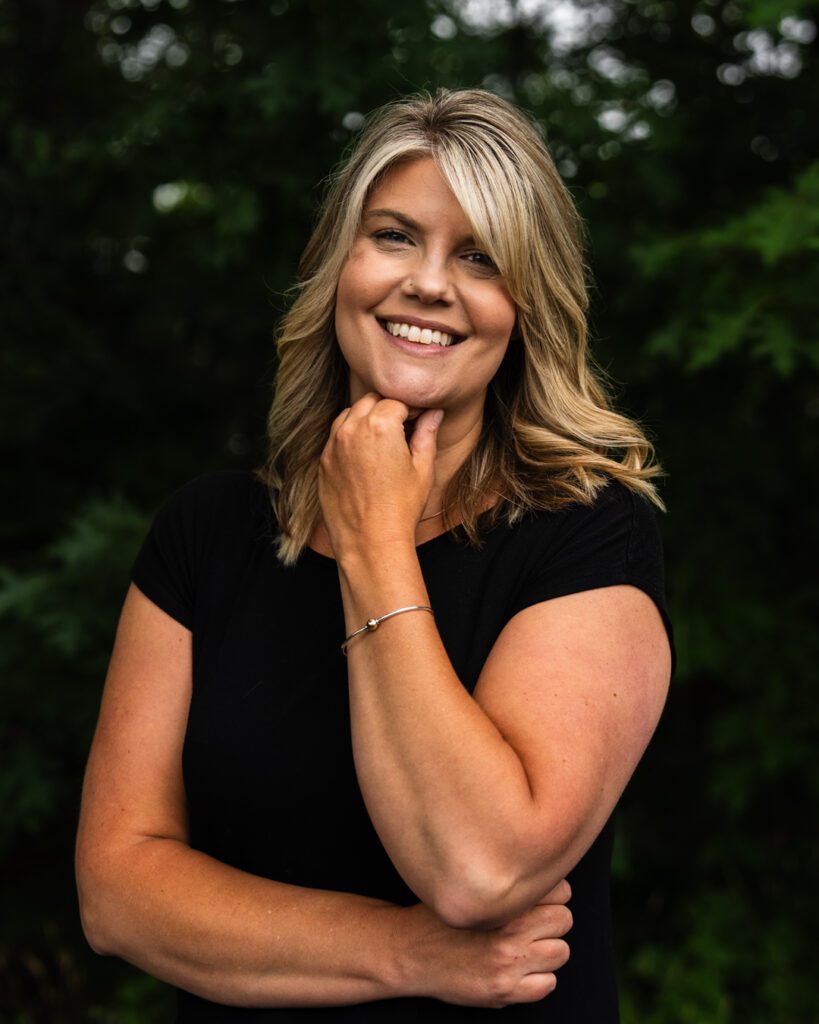 Leigh Benner smiling with hand under chin wearing black shirt.