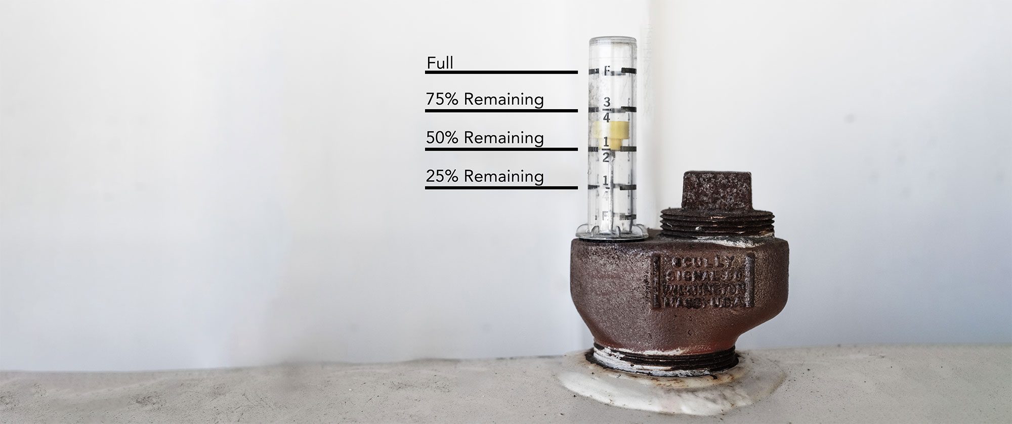 A metal and glass oil tank gauge sitting on top of a white oil tank.