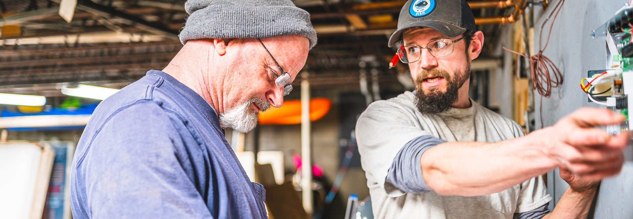 Two men work on a heat pump in a home's basement.