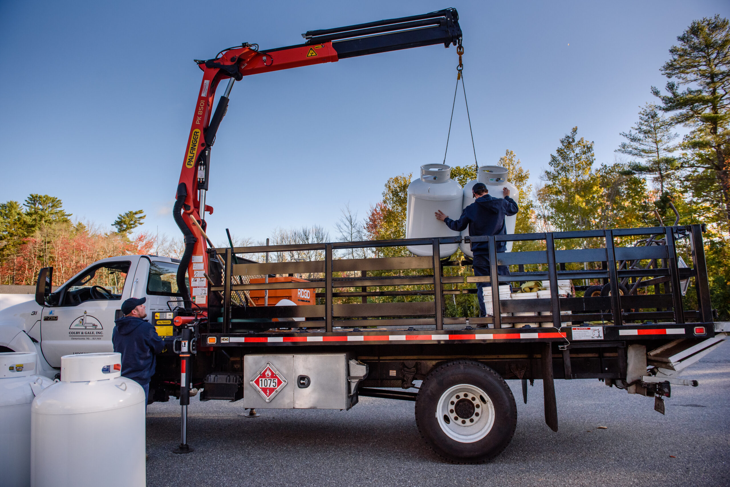 Colby & Gale employees using crane to load propane tanks on truck.