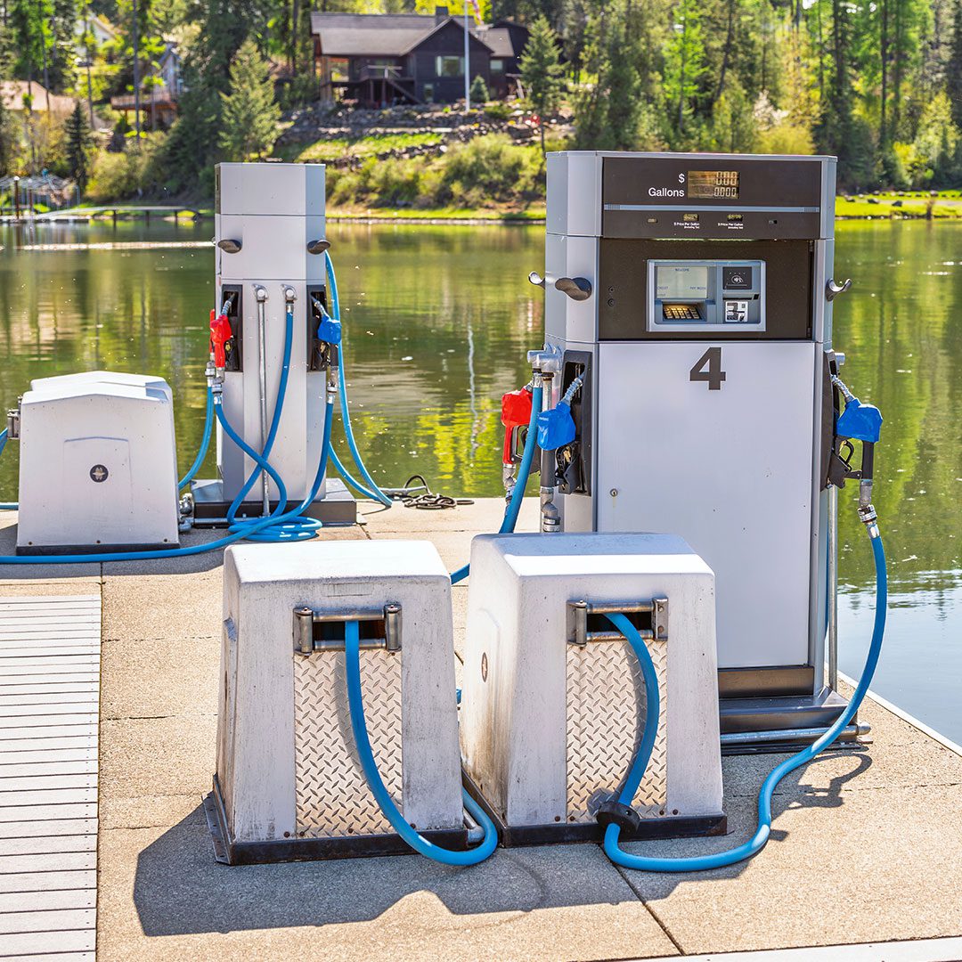A diesel fuel pump sits on a gas dock on a lake by the water.