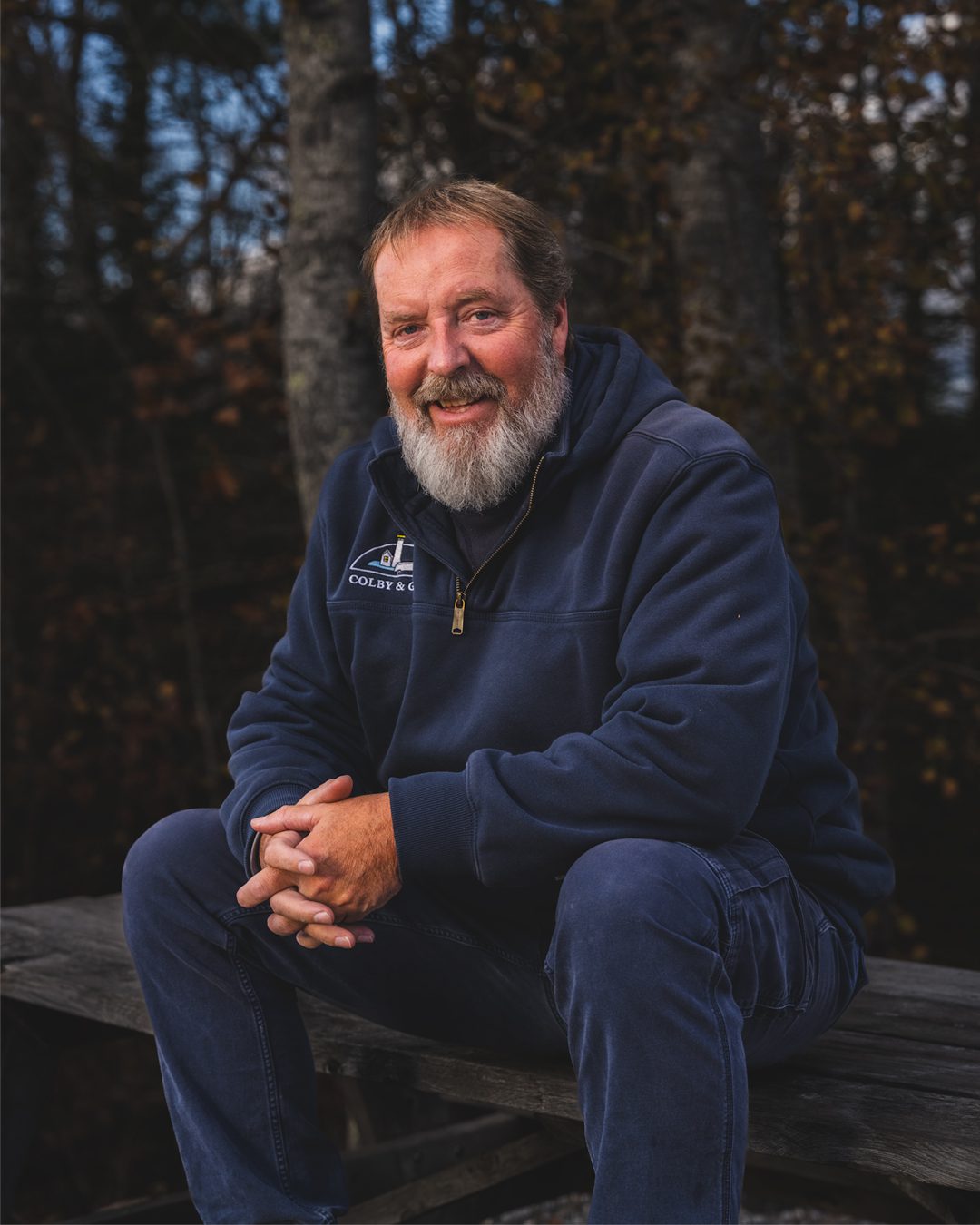 Shawn Brown with hands clasped sitting on top of picnic bench. 