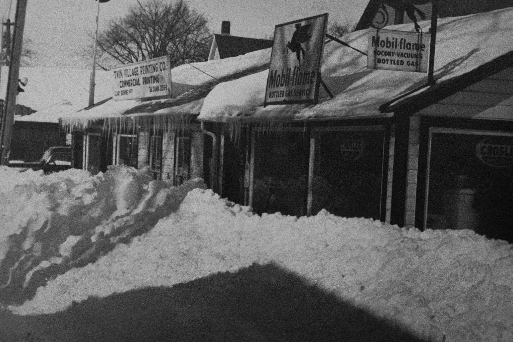 Historic massive snow piles in downtown Damariscotta, Maine, during the 1960s, showcasing the winter weather challenges Colby & Gale has navigated for decades in Lincoln County.