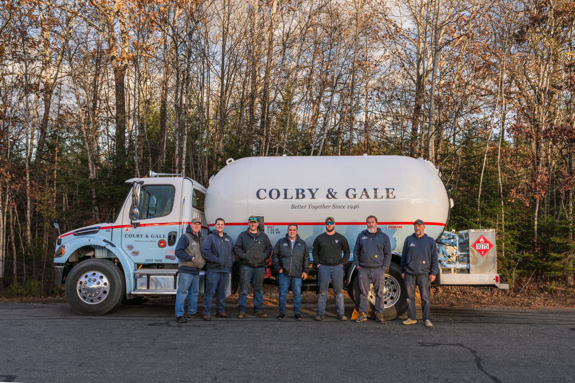 Group of men in front of propane truck as the sun sets